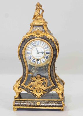 a gold and black clock sitting on a white surface