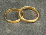 two gold wedding rings sitting on a black surface
