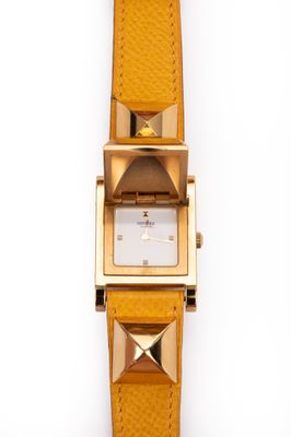 une image représentant une montre jaune dont le cadran est orné de pyramides