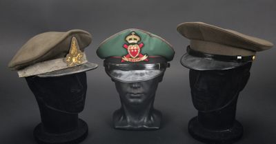 trois casquettes militaires sur une tête de mannequin, sur fond noir