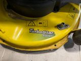 a close up of a yellow lawn mower on the ground