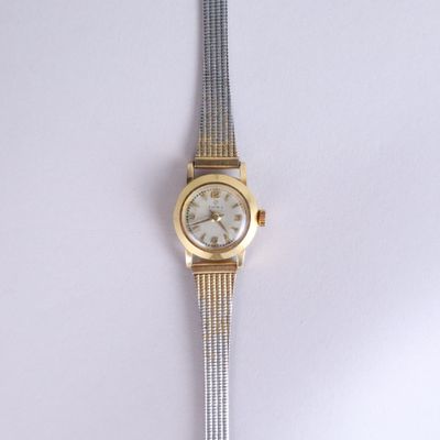 a silver and gold wrist watch on a white surface