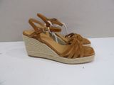 tan sued wedged sandals with braid straps on a white surface
