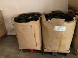 deux sacs remplis de bouteilles noires posés sur une palette dans un entrepôt
