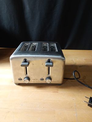 une image représentant un grille-pain posé sur une table, à côté d'un chargeur