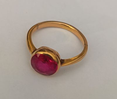 a close up of a gold ring with a pink stone