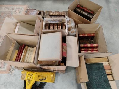 plusieurs cartons remplis de livres et un pistolet à colle posés par terre