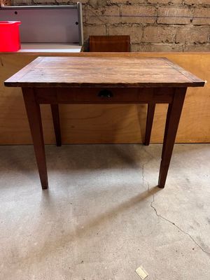 une vieille table en bois avec un tiroir en dessous, dans une pièce