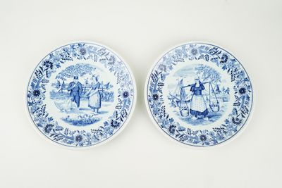 deux assiettes bleues et blanches sur lesquelles figurent des personnages, posées sur une table