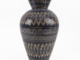 a blue and black vase sitting on a white surface