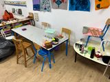a room with a table, chairs, and paintings on the wall