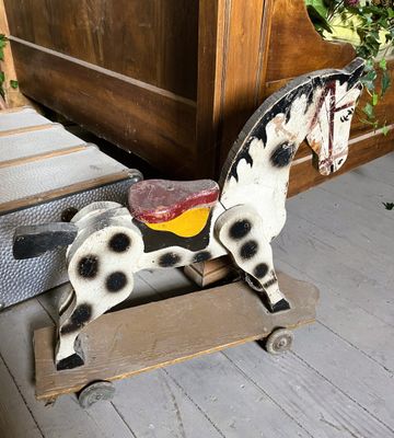 un cheval en bois posé sur une charrette en bois