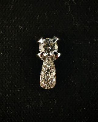 un gros plan d'un pendentif en diamant posé sur une surface noire