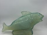 une figurine de poisson en verre posée sur une surface blanche