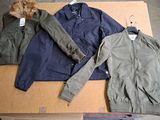 two jackets and a jacket sitting on top of a cardboard box