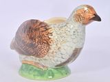 un oiseau en céramique posé sur un socle vert