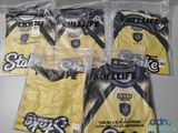 Trois sacs contenant des t-shirts jaunes ornés de logos noirs et blancs sont posés sur une table