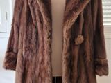 un manteau de fourrure marron posé sur un mannequin devant une vitrine