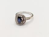 a close up of a ring on a white surface with a blue stone