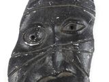 an image of a black stone mask with a face on it