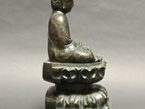 bronze statue of a seated person on a lotus flower base