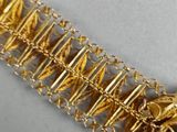 a close up of a gold chain bracelet on a white surface