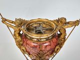 a gold and red vase with a clock on it