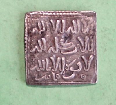 an old silver coin with writing on it sitting on a green surface