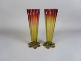 une paire de vases en verre rouge et jaune posés sur une surface blanche