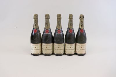 quatre bouteilles de champagne sont alignées sur une surface blanche