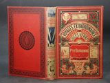 an old book with a red cover sitting on top of a table