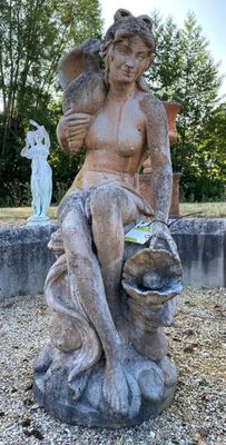 a statue of a woman sitting on a rock in a garden