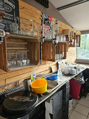 une cuisine équipée d'une cuisinière, d'un évier et d'étagères remplies de verrerie