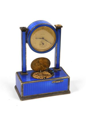 une petite horloge bleue sur laquelle est posée une pièce de monnaie