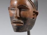 une photo d'une sculpture représentant une tête en bois posée sur un socle en métal