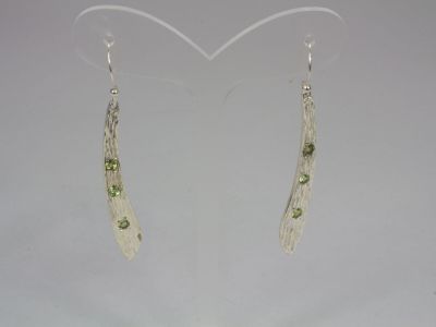 silver and peridot earrings on a white background