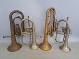 three brass trumpets sitting next to each other on a white surface