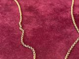 a gold necklace with a small bar on a chain