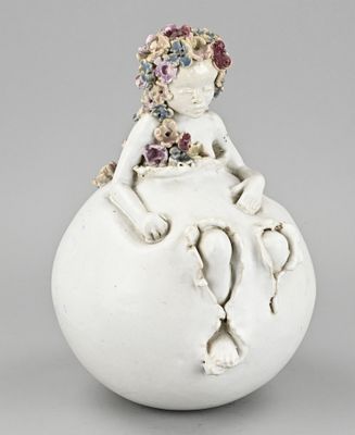 a white vase with a little girl sitting on top of it