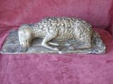 a statue of a sheep that is laying down on a table
