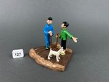 two figurines of a man and a dog on a table