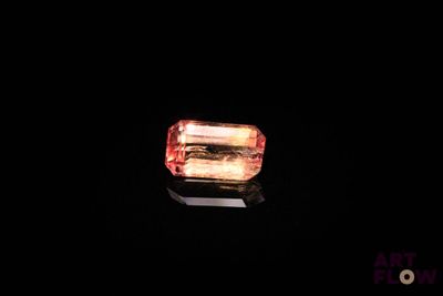 un gros plan d'un diamant rouge et jaune sur une surface noire