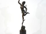 une statue en bronze représentant une femme tenant un oiseau, posée sur un socle