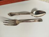 two silver spoons and a fork on a table