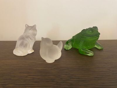 three figurines of cats and a frog sitting on a table