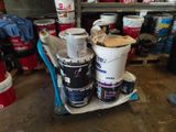 several buckets of paint are stacked on a cart in a garage