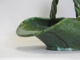 a green bowl with a handle on a white surface
