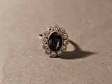 une image représentant une bague ornée d'une pierre noire entourée de diamants blancs