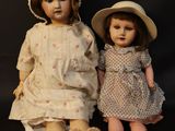 two dolls sitting next to each other on a black background