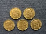 four gold sovereigns of different sizes and shapes on a blue surface